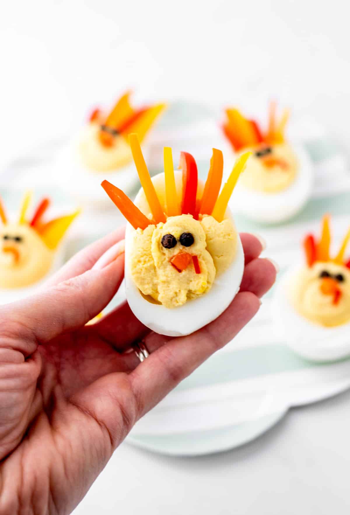 A hand holding up a turkey shaped deviled egg.
