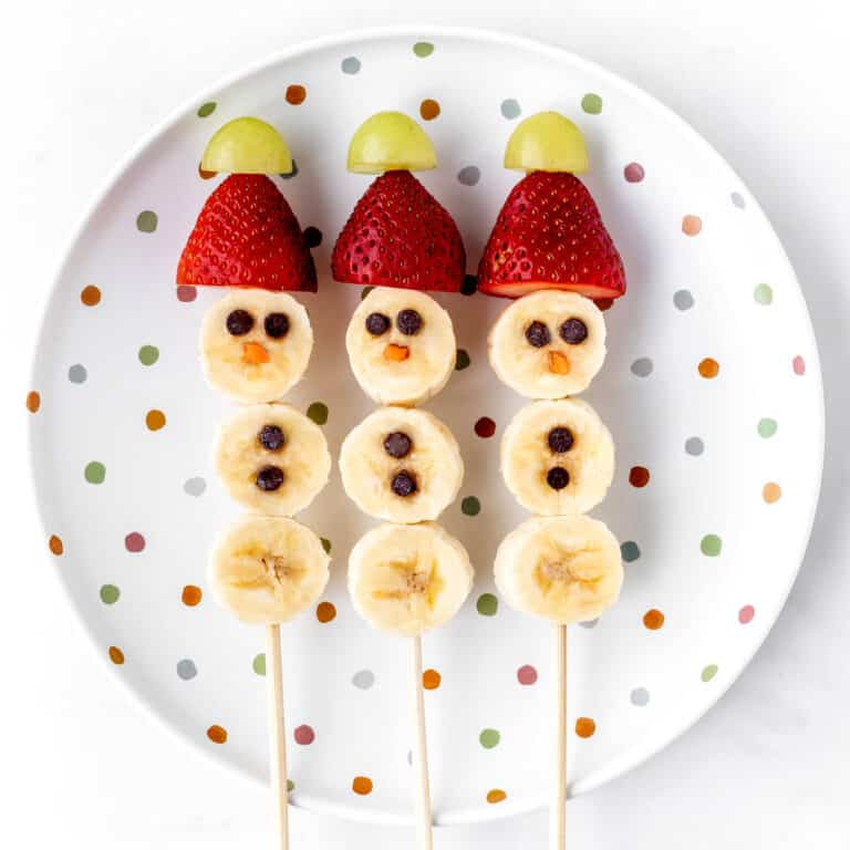 Three banana snowmen on sticks on a polka dot plate.
