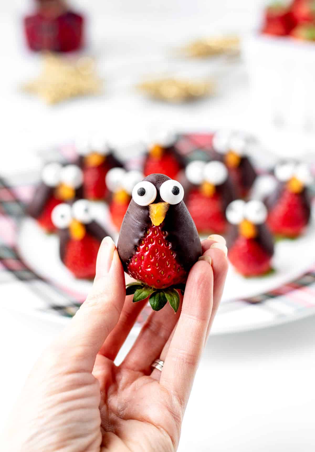 A close-up of a strawberry penguin being held in someone's hand.