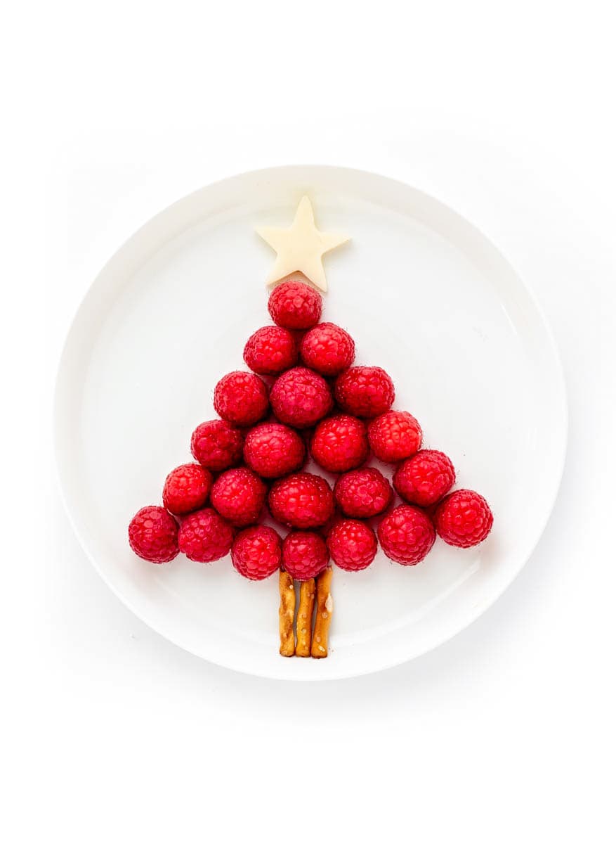 A Christmas tree assembled with raspberries, pretzel sticks and topped with a star.