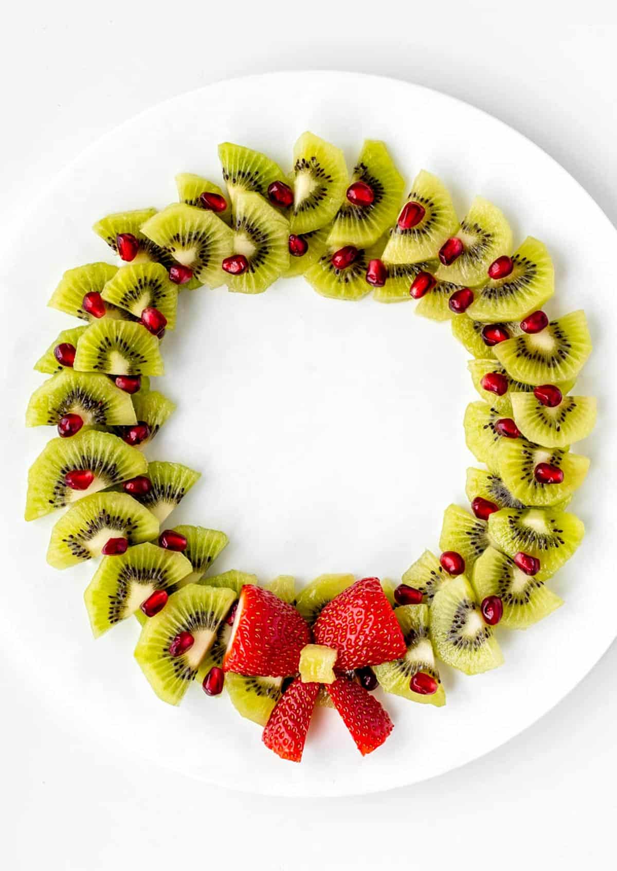 A Christmas fruit wreath on a white, circular platter.