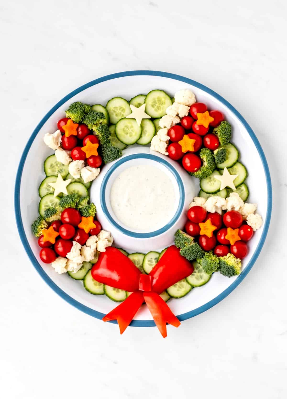 Birds-eye view of the Christmas wreath veggie tray with bell pepper bow and the dip in the center.