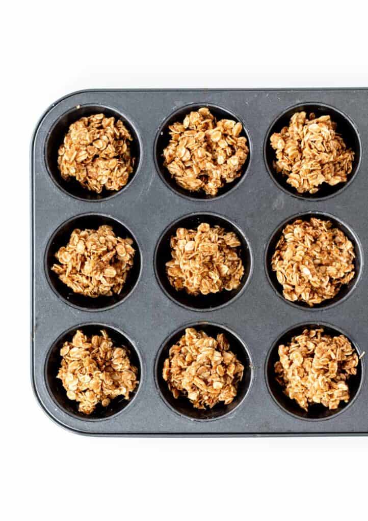 The granola mixture in the muffin cups, prior to baking.