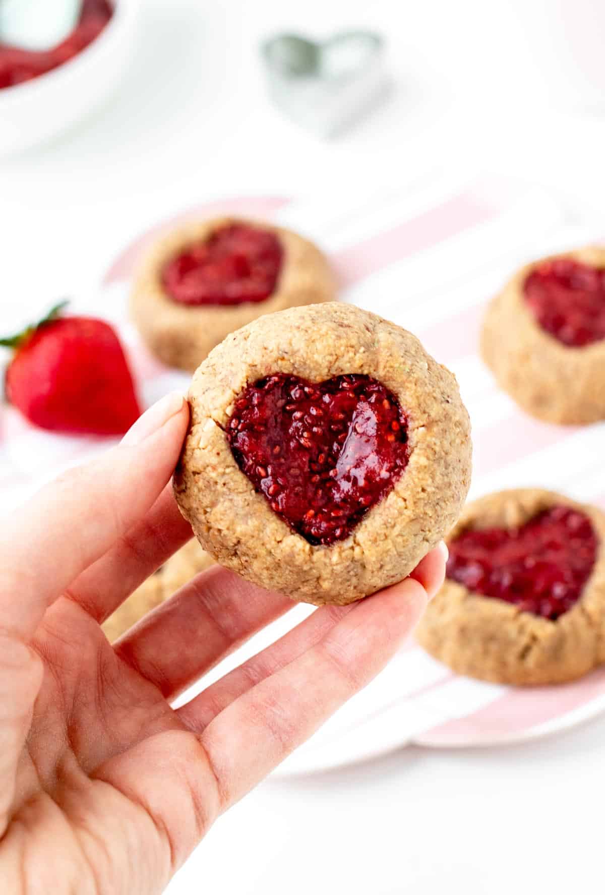 A close-up of the jam filled heart cookies being held in someone's hand.