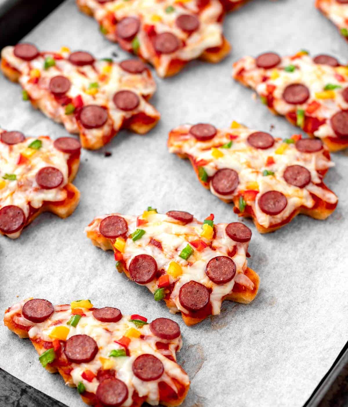 The mini Christmas tree pizzas on a baking sheet after they have cooked in the oven.