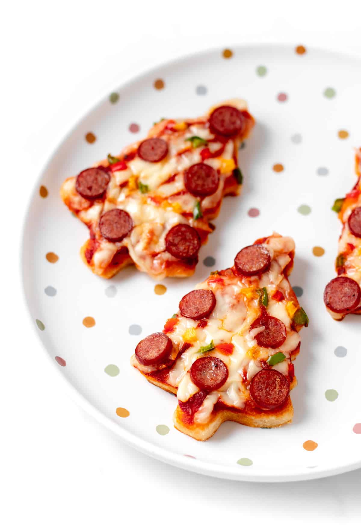 Mini Christmas tree pizzas after they have baked in the oven on a decorative plate.