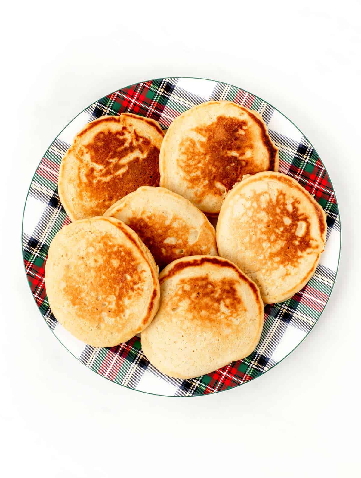 A plate of cooked pancakes on a plaid plate.