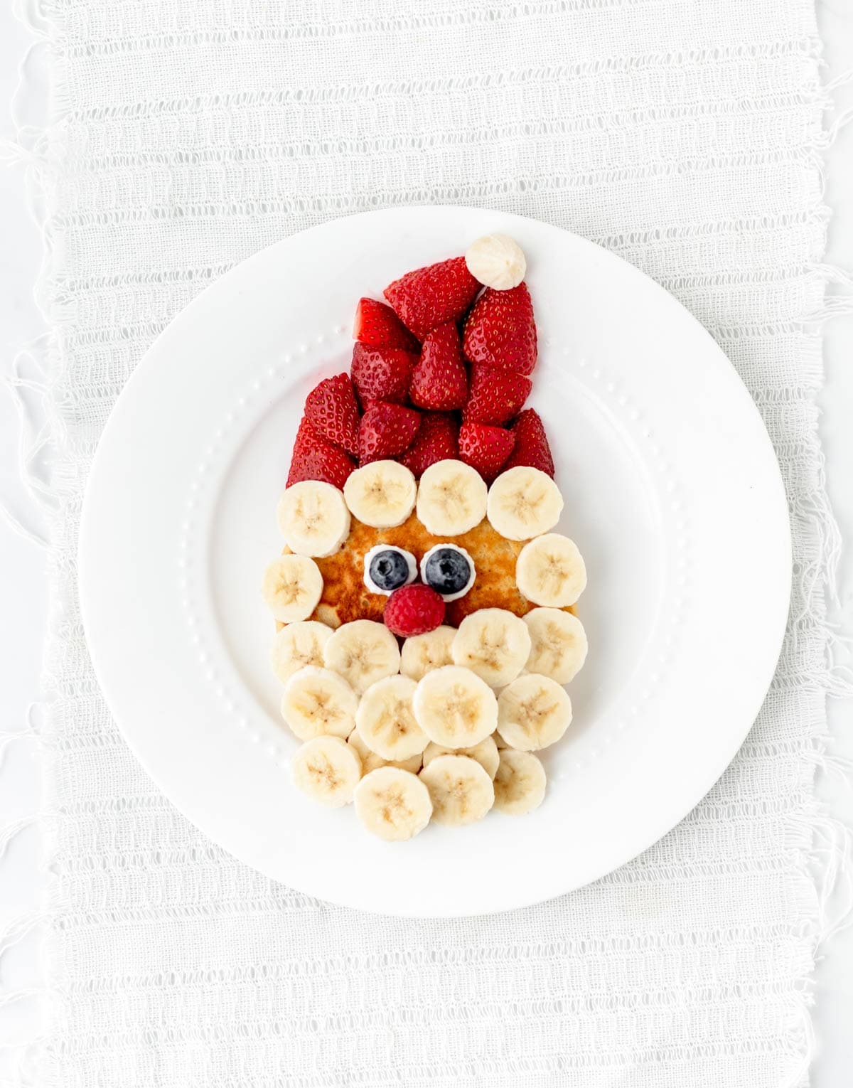 A Santa face pancake with strawberries, bananas, blueberries and raspberries.