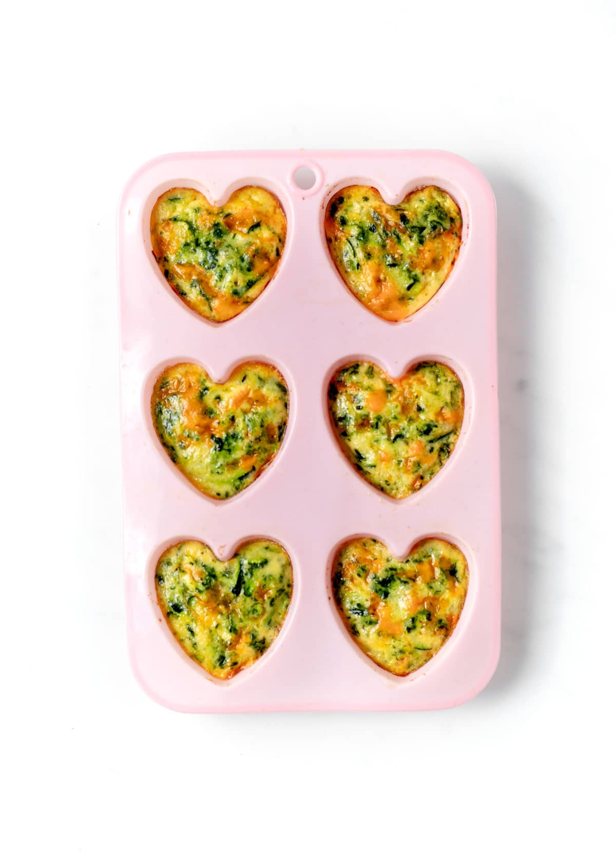 6 zucchini frittata muffins in heart shaped molds.