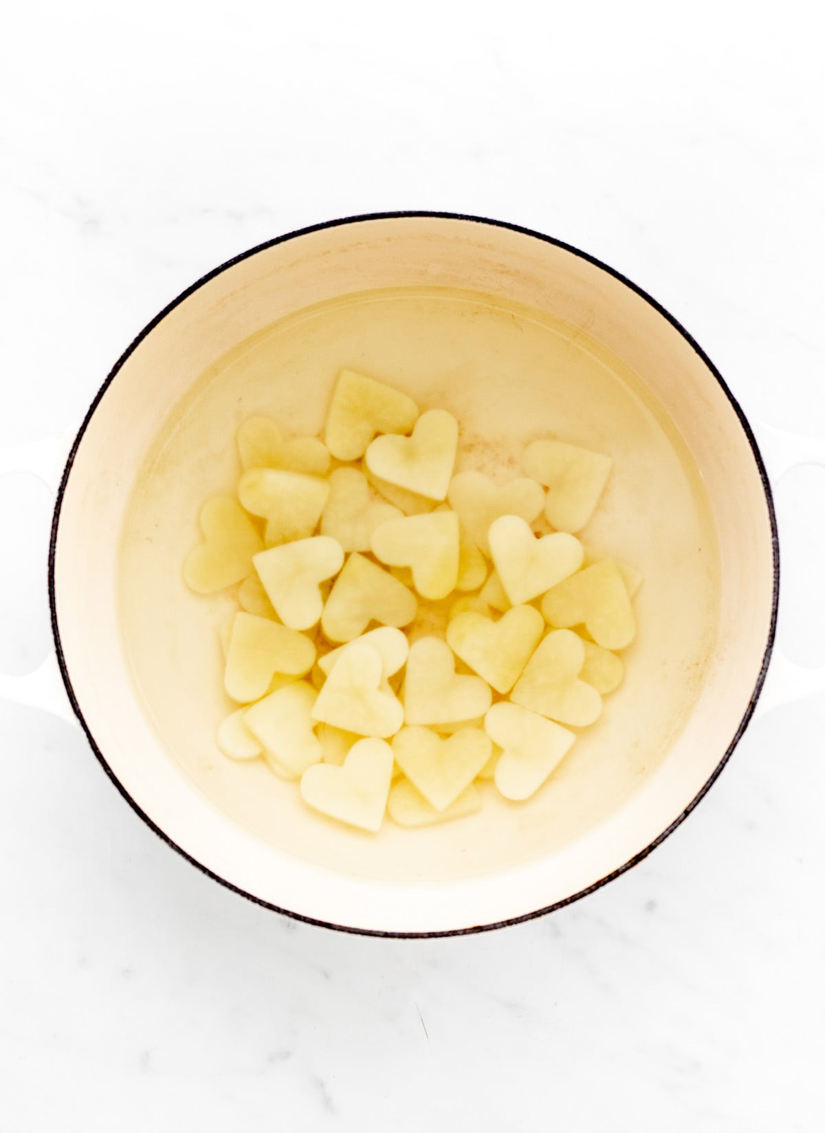 Potatoes cut into heart shapes and parboiled in a pot of water before baking.