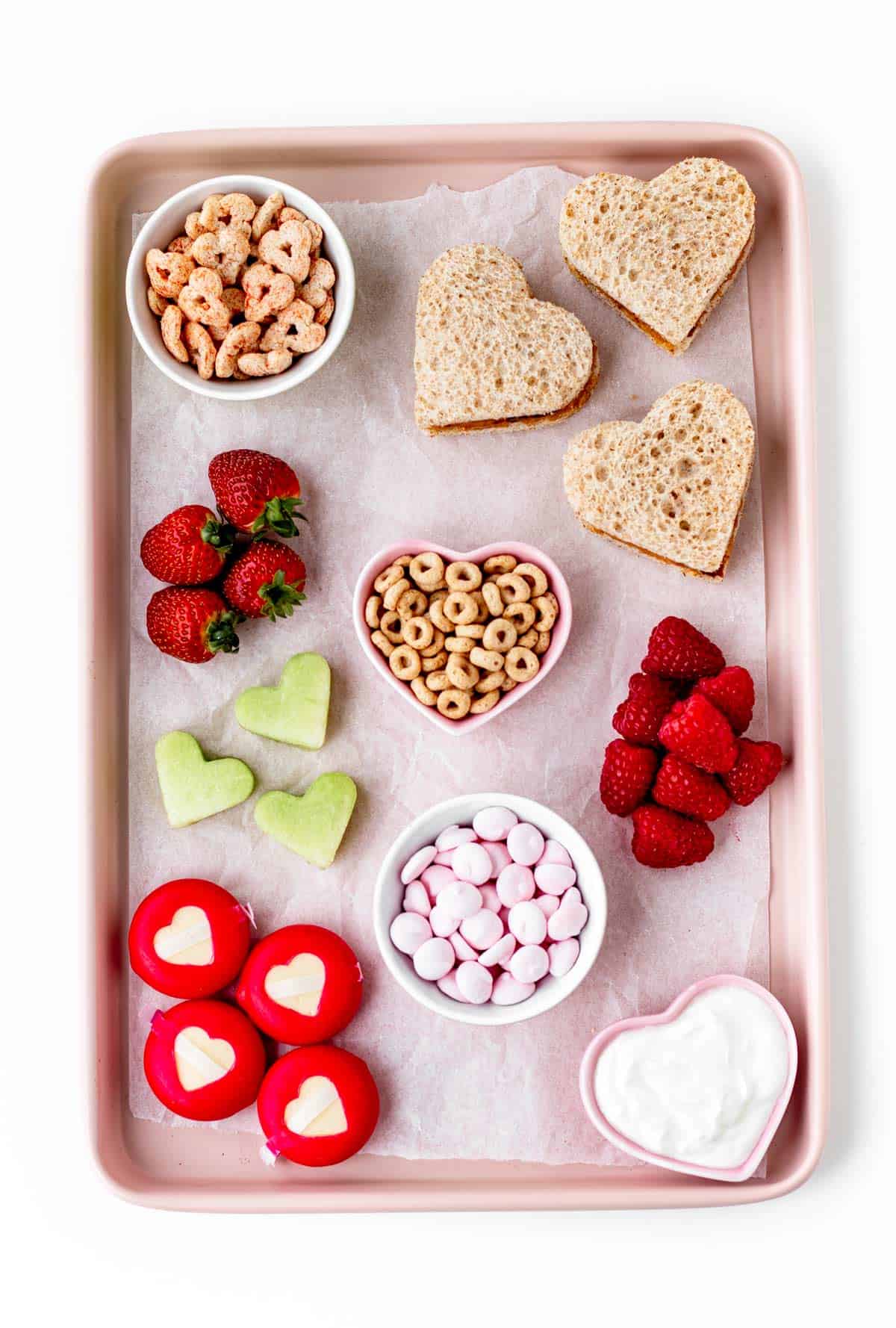 A birds-eye view of the ingredients for the charcuterie board with heart-shaped snacks.
