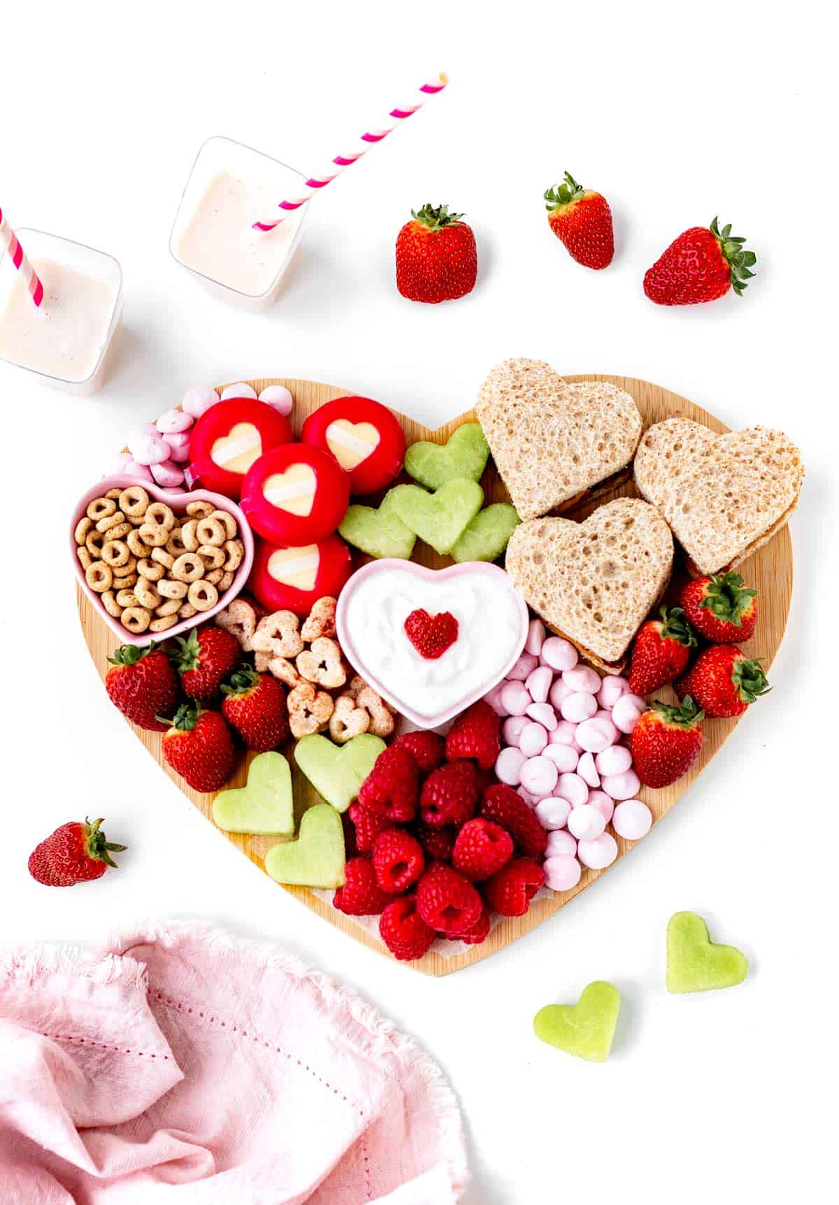 A birds-eye view of the heart shaped charcuterie board, with fresh strawberries surrounding the edges.