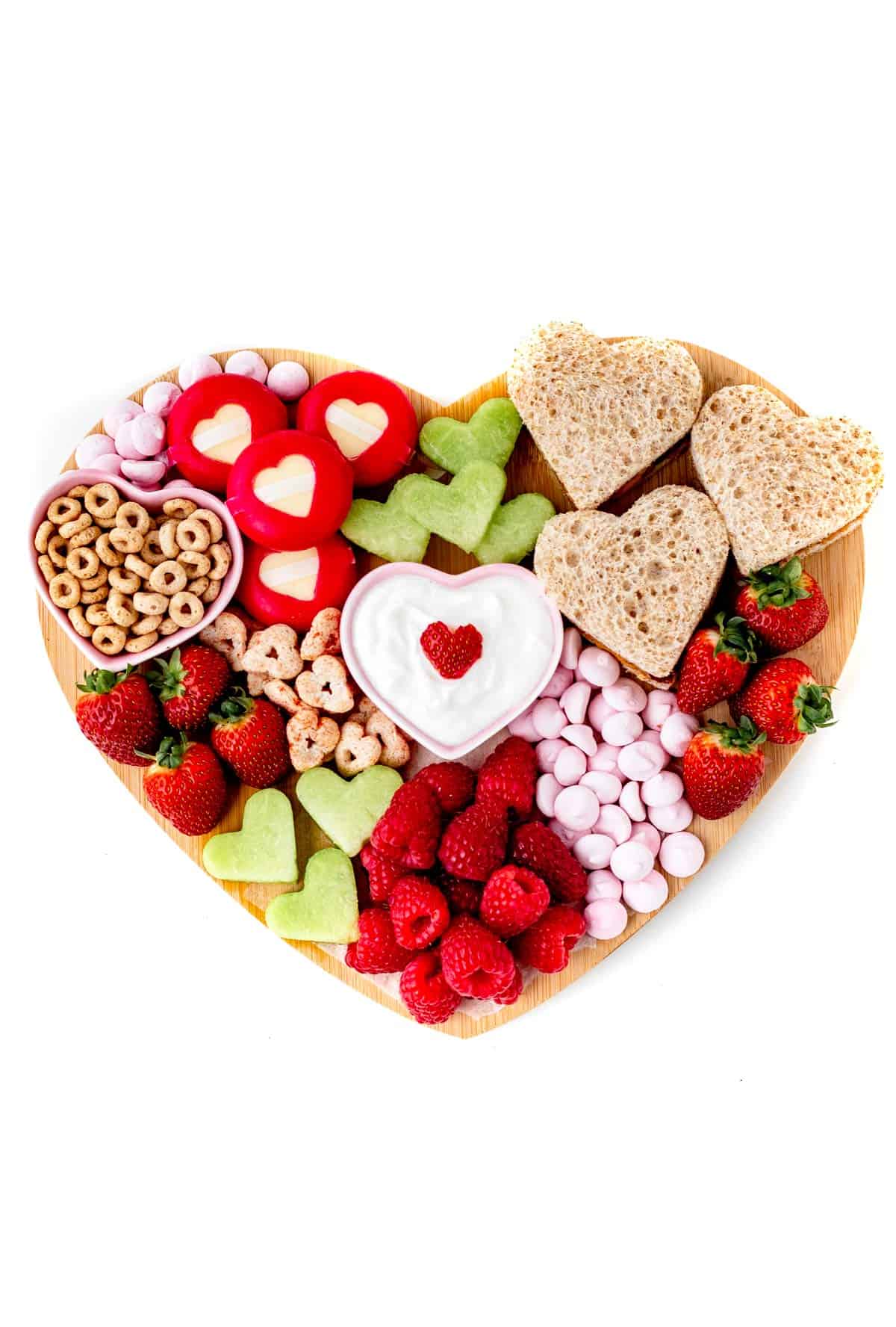 A birds-eye view of the heart-shaped snacks on a heart shaped charcuterie board.
