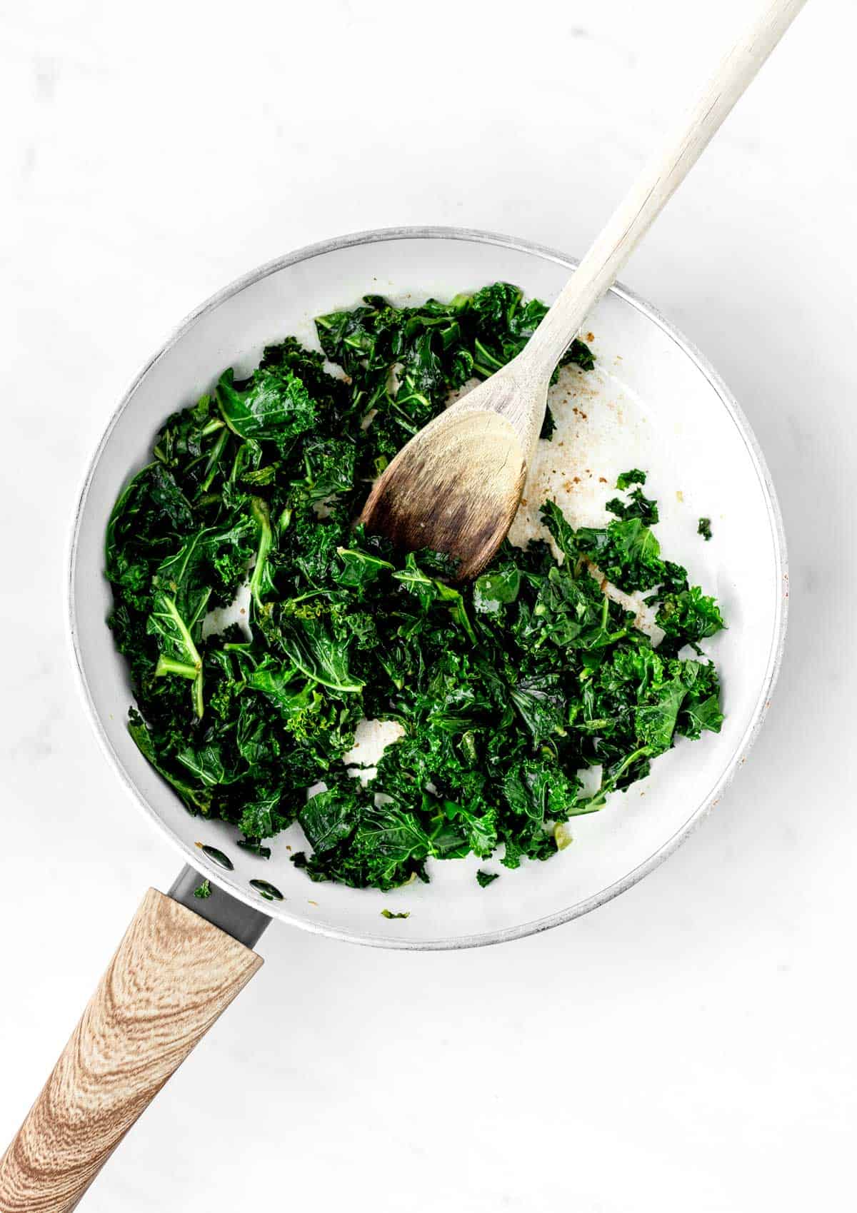 Cooking kale in a frying pan, until soft and fragrant.