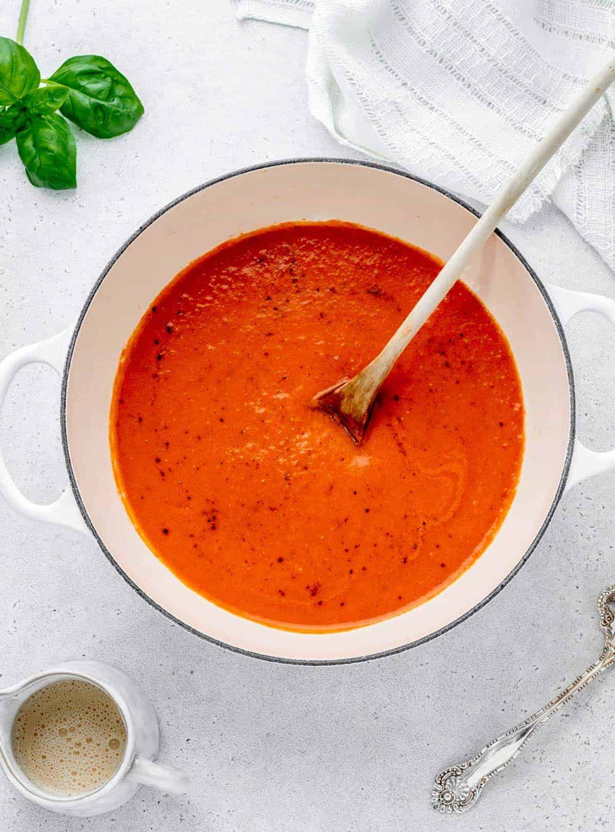3 ingredient tomato soup in a large pot on the counter with a spoon in it.