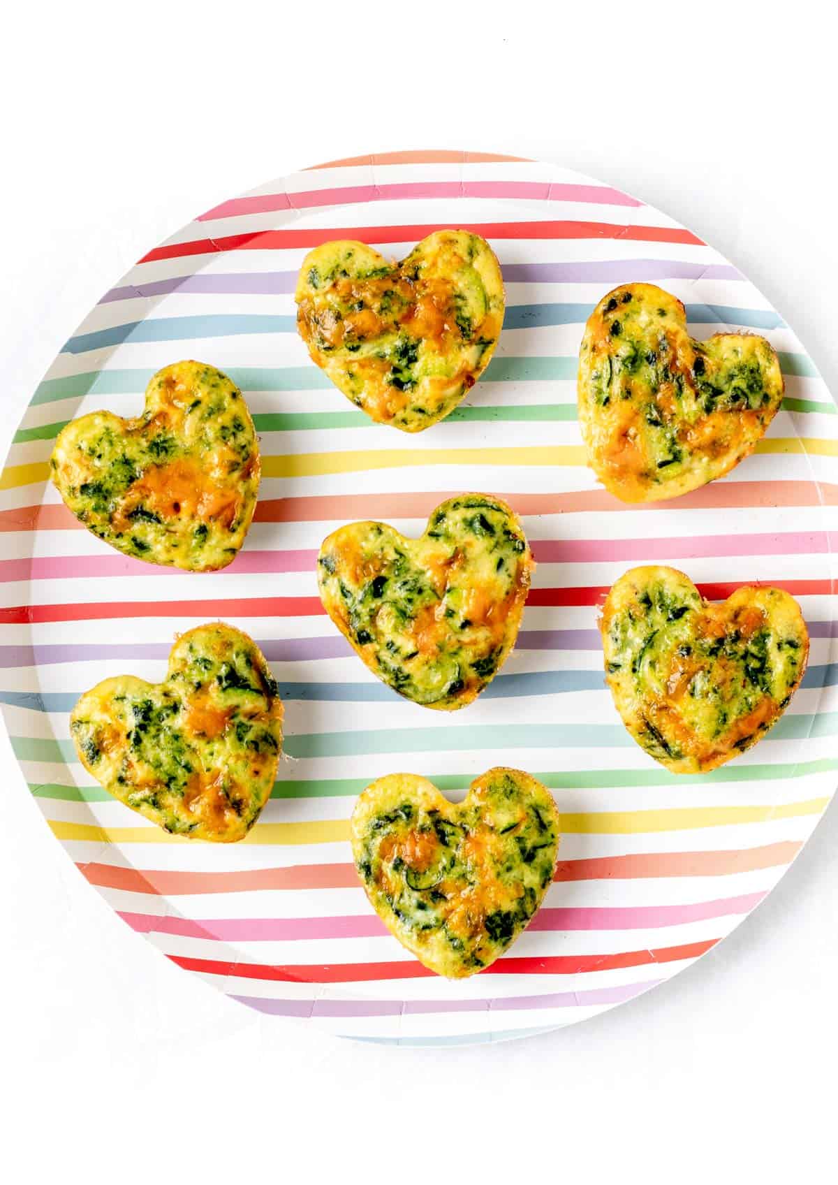 A birds-eye view of the zucchini frittata muffins on a striped plate.