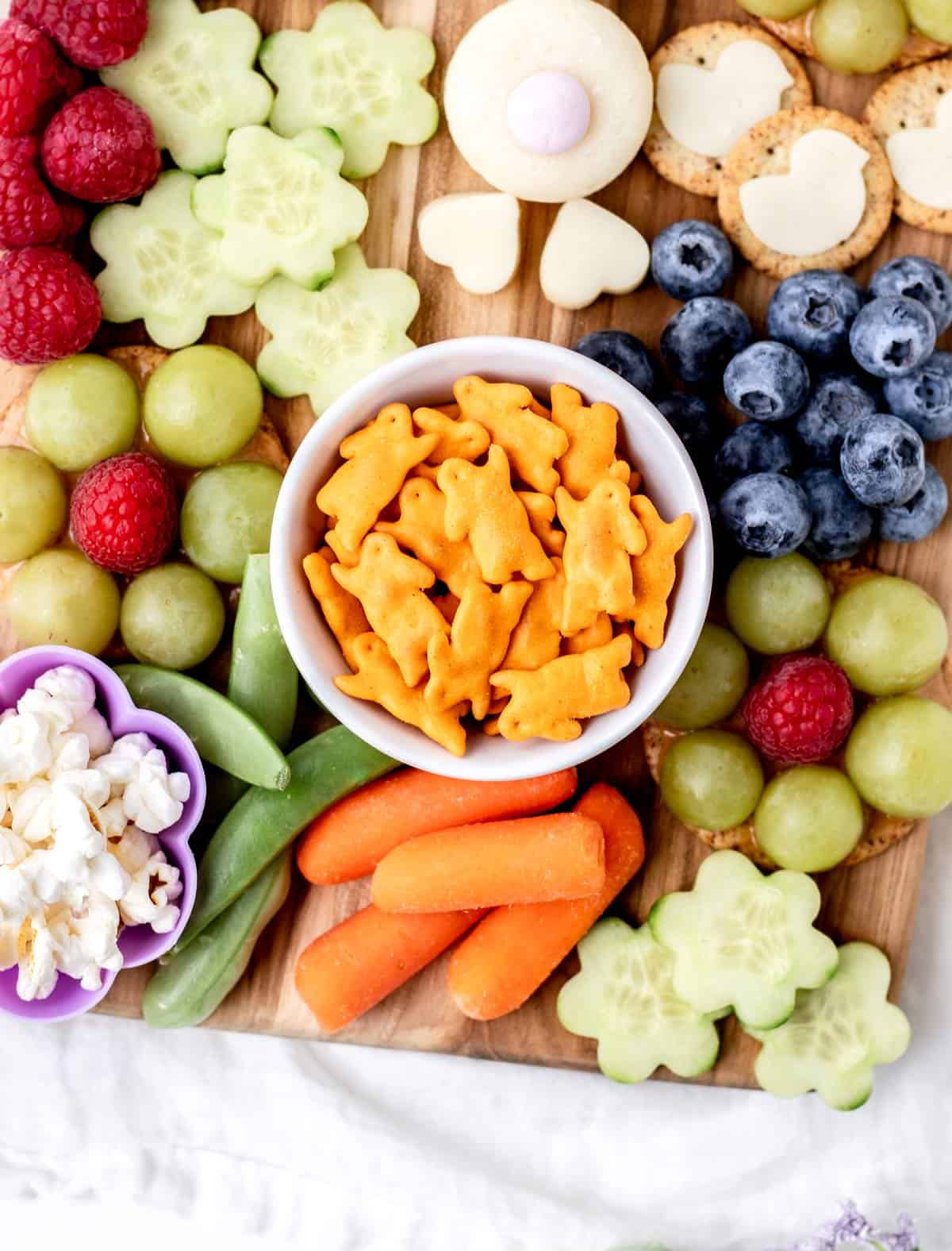 A close-up of the Annie's bunny crackers in the center of the Easter bunny board, surrounded by grapes, carrots, and blueberries.