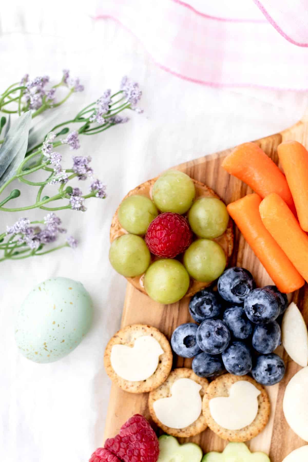 A close-up of the side of an Easter bunny board, showcasing the grape nests, carrots, and blueberries.