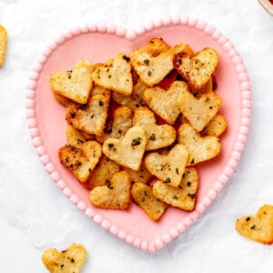 Roasted heart shaped potatoes on a pink heart-shaped plate.